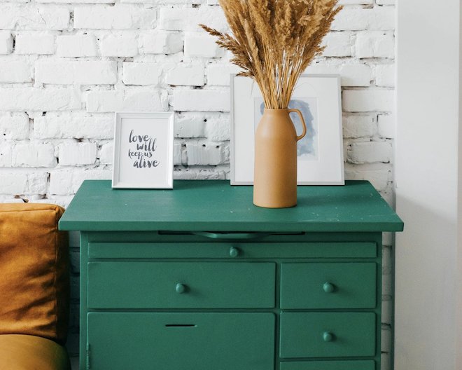 Beautifully decorated room. A table with a bucket with a plant inside. Behind there are some pictures